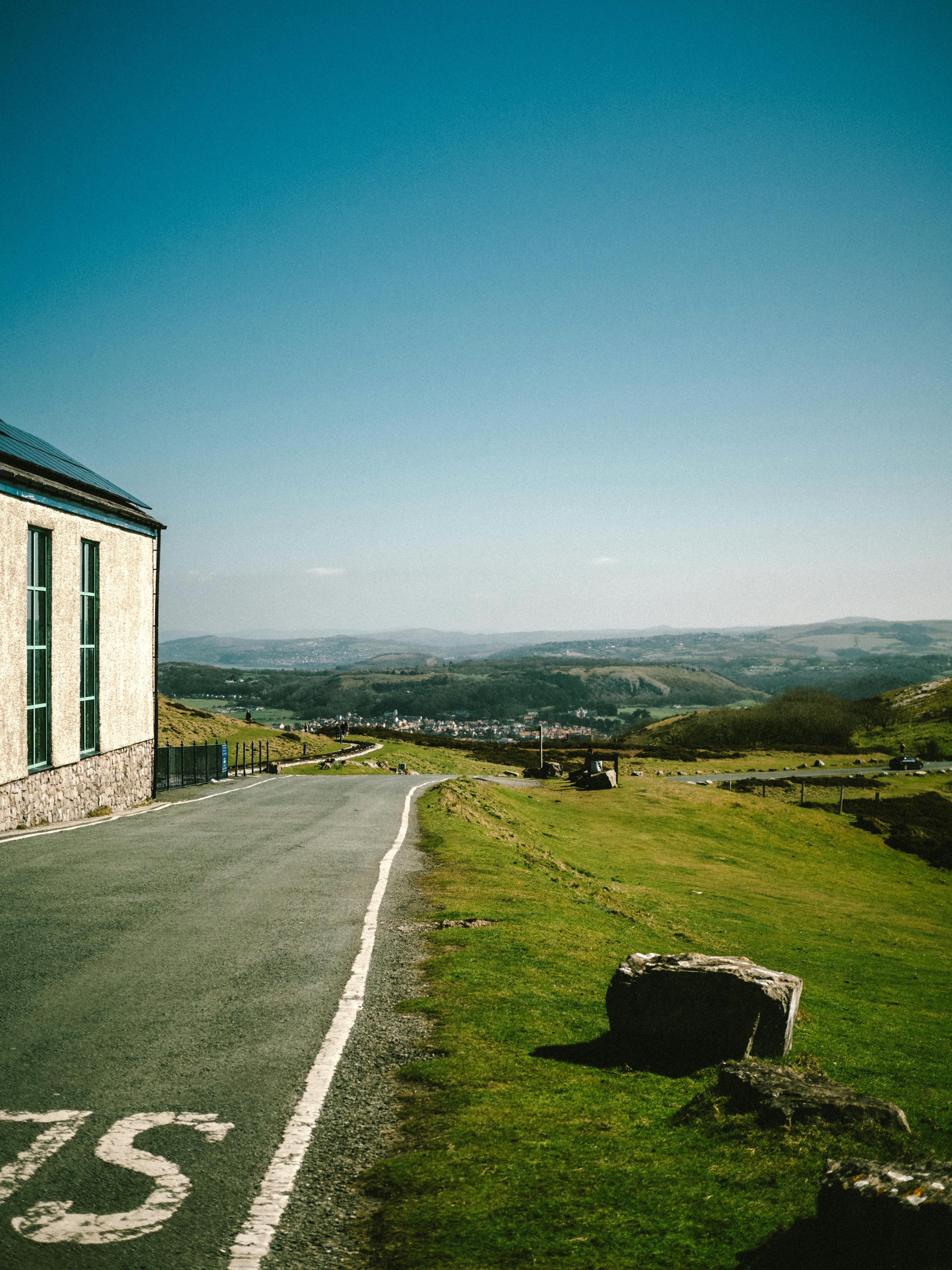 A picturesque view of a road winding through the lush hills of Wales under a clear blue sky.