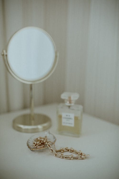 Photo of a Gold Necklace Near a Mirror