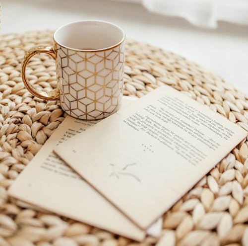 Free Pages of Book and Ceramic Cup on Brown Woven Surface Stock Photo