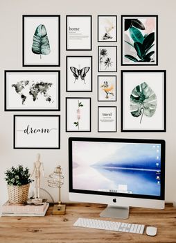 Stylish home office desk setup with framed art and a sleek computer monitor.