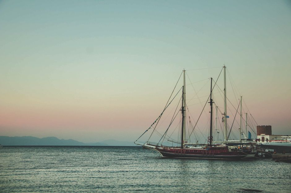 Ultimate All Inclusive Cruise Sailing Cruise to Delos & Rhenia Beaches Review: A Magical Sunset Sailing Adventure in Greece Review 2026 - A tranquil sunset over Rhodes harbor featuring a majestic ship silhouette.