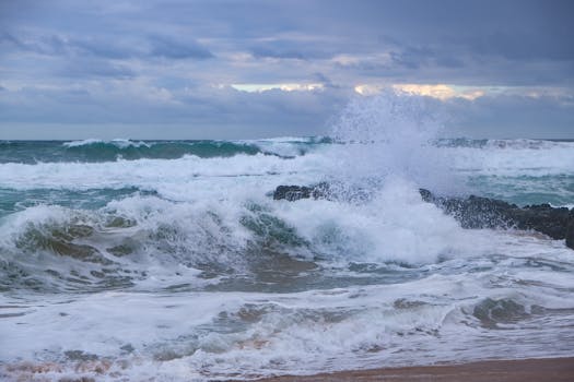Powerful ocean waves crashing on a rocky shore under a moody sky.