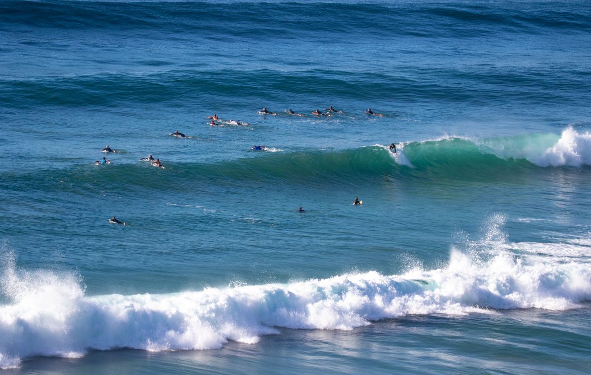 Crowded surf lineup with many surfers in the water during peak summer season