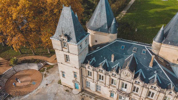 Drone shot of a historic château surrounded by vibrant autumn foliage in Bordeaux, Nouvelle-Aquitaine, France.