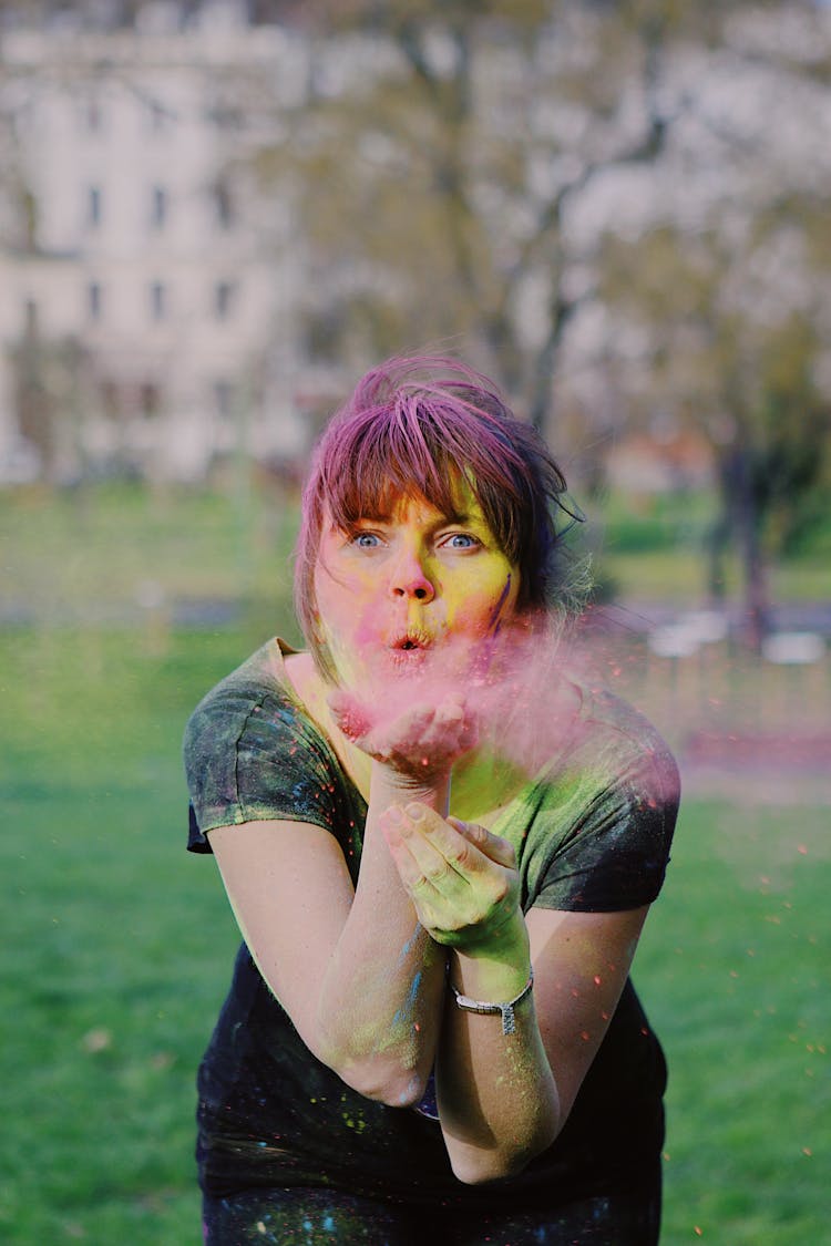 Close-Up Shot Of A Woman With Blue Eyes Blowing Holi Powder From Her Hand