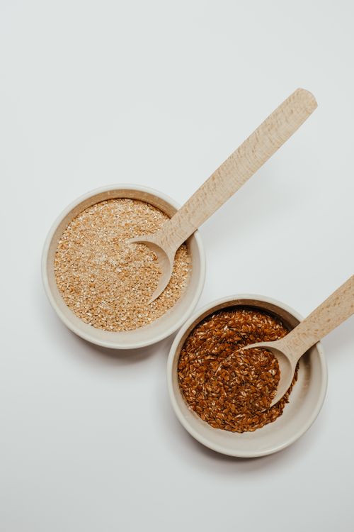 Free Elegant flat lay of flax and oat seeds in ceramic bowls with wooden spoons on a white background. Stock Photo