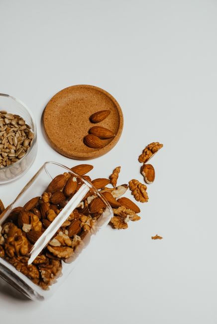 Incorporate dry fruits into daily diet - Ways to Incorporate Dry Fruits in Breakfast, Snacks, and Meals | A collection of almonds, walnuts, and sunflower seeds in a glass jar on a minimalist white surface.