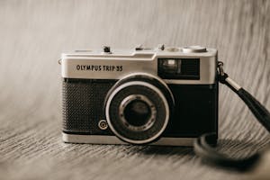 Old fashioned photo camera with title and buttons on metal frame with strap on blurred background