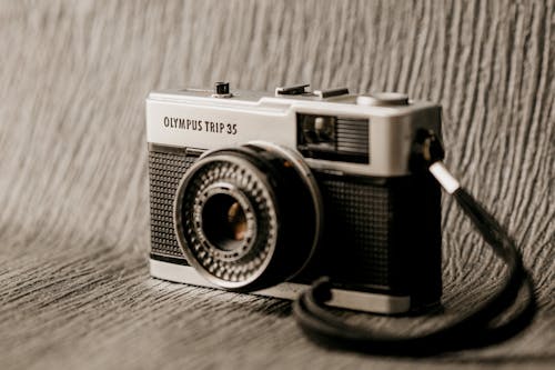 Old fashioned point and shoot photo camera with inscription and flash on metal frame with strap