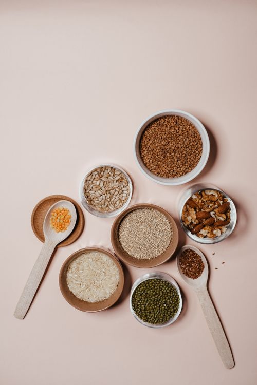 Free Flat lay of various grains and nuts in bowls and wooden spoons on neutral background. Stock Photo