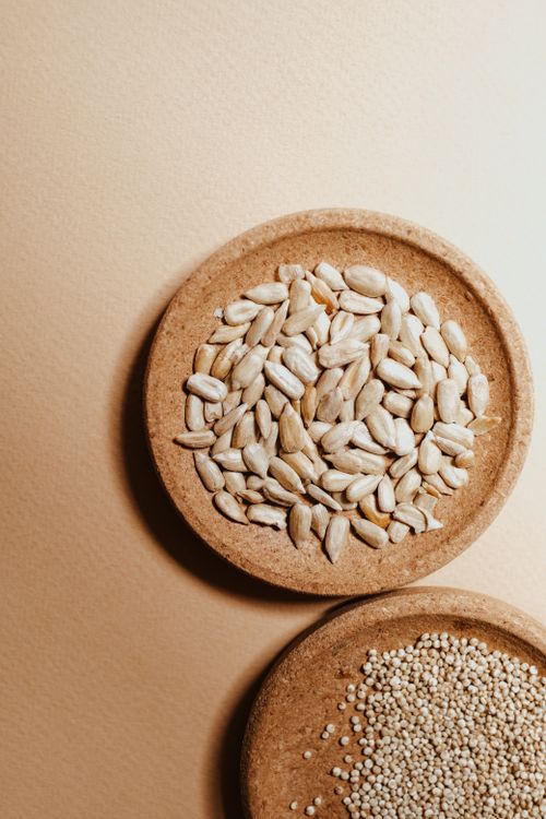 Free A close-up view of peeled sunflower seeds and quinoa on a wooden plate. Stock Photo
