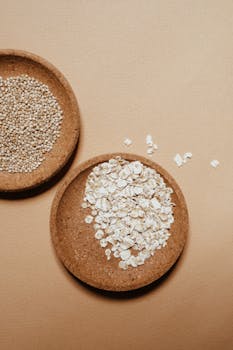 High angle shot of oats and grains in eco-friendly bowls on a brown background.