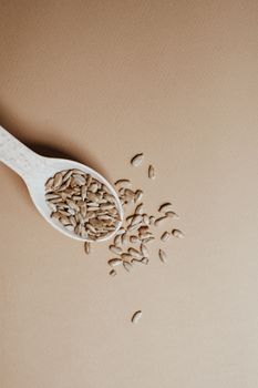 Close-up of a spoonful of organic seeds on a brown background, emphasizing natural and healthy eating.