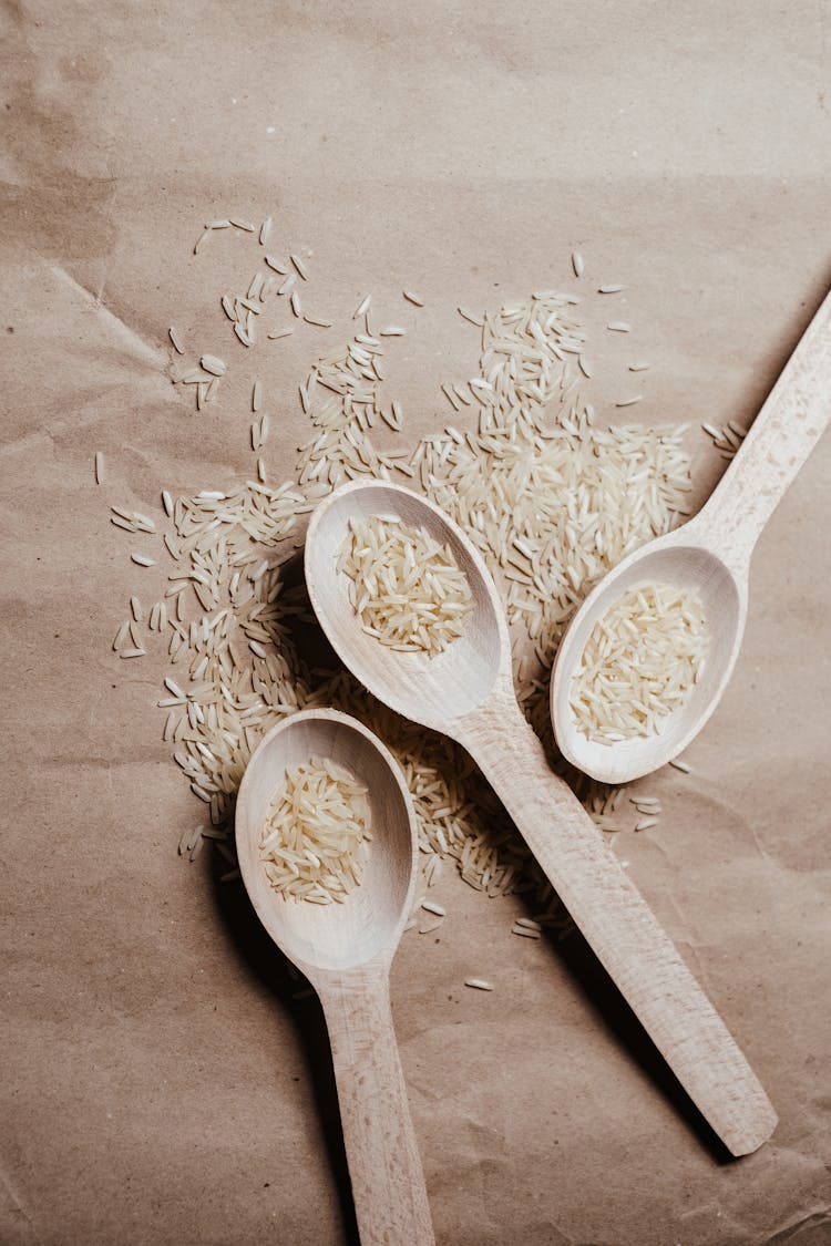 White Rice Grains On Wooden Spoons