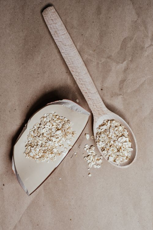 Free Close-up of a wooden spoon filled with organic oats on a brown paper background. Stock Photo