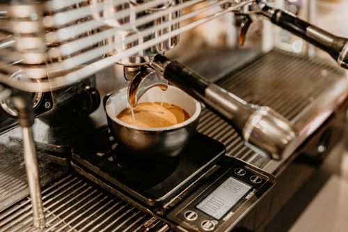 Free Mug of freshly brewed aromatic coffee placed on cup holder of modern coffee machine in contemporary cafeteria with professional equipment Stock Photo
