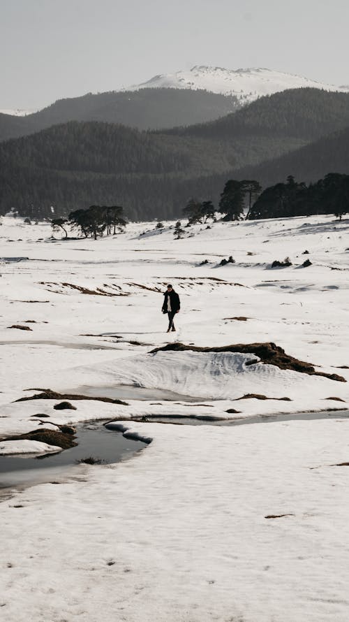 Free A Person Walking on a Snow Covered Field Stock Photo