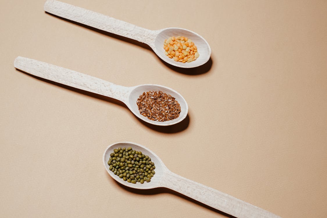 Three wooden spoons with beans and dals