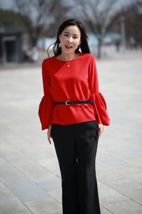 Woman in Red Long Sleeve Shirt and Black Pants Standing on Road