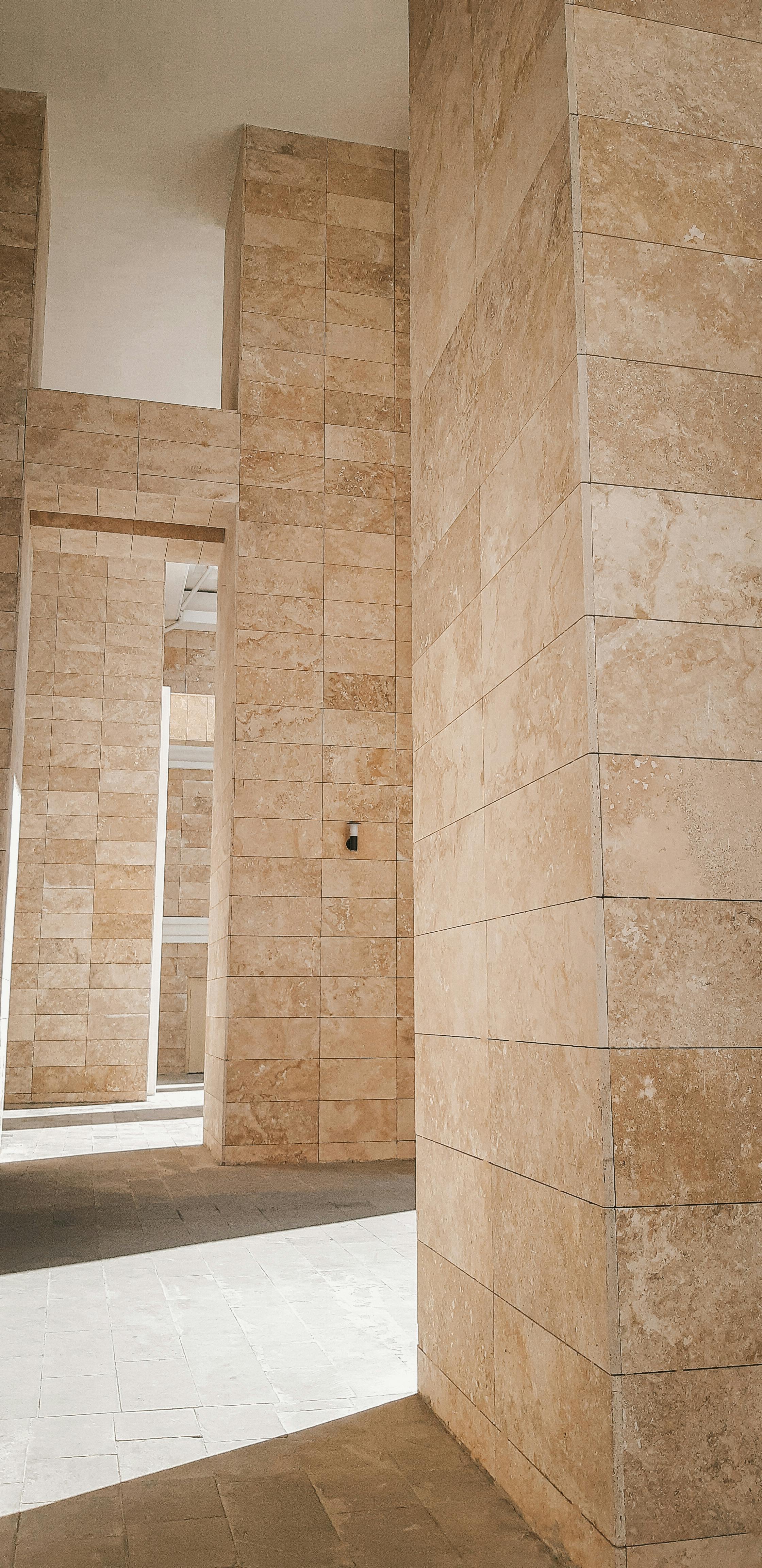Stone-clad interior wall with warm natural light — thermal mass in high-design architecture