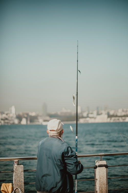 Man in Blue Shirt Fishing on Sea