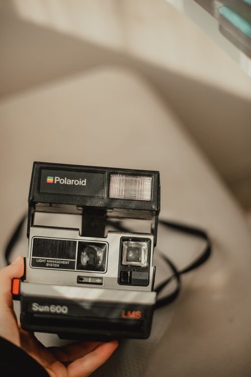 Free Close-up of a classic Polaroid Sun 600 camera held indoors, evoking nostalgia. Stock Photo