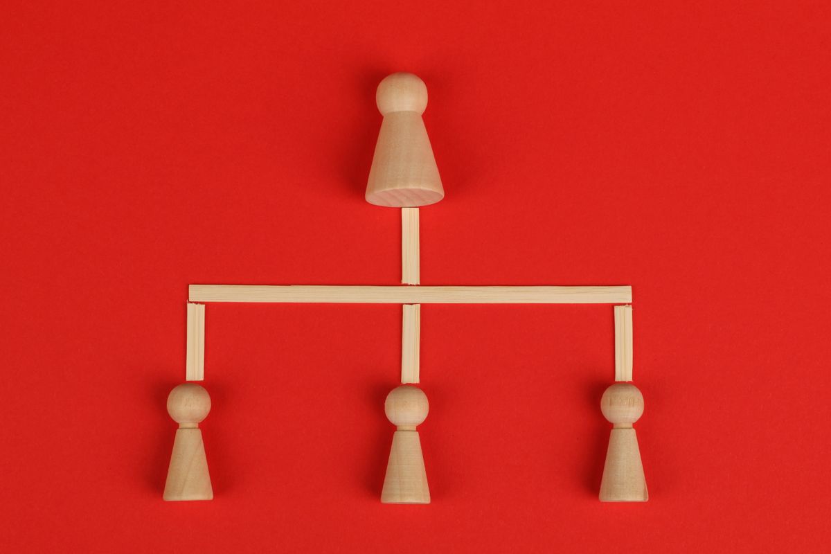 Wooden figures arranged as an organization chart on a red background