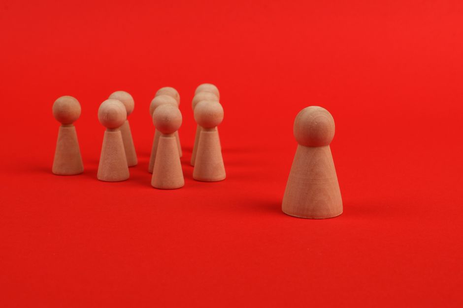 Wooden figures on a vibrant red background illustrating leadership and teamwork concepts.