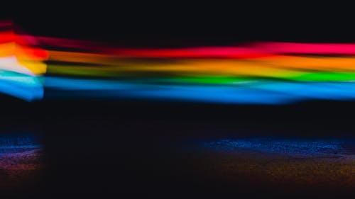 Colorful abstract background with blurred glowing rainbow lights in modern dark studio with black wall and creative bright optical effect