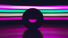 Round disk placed on black surface against abstract background with bright colorful stripes glowing in dark studio with purple illumination