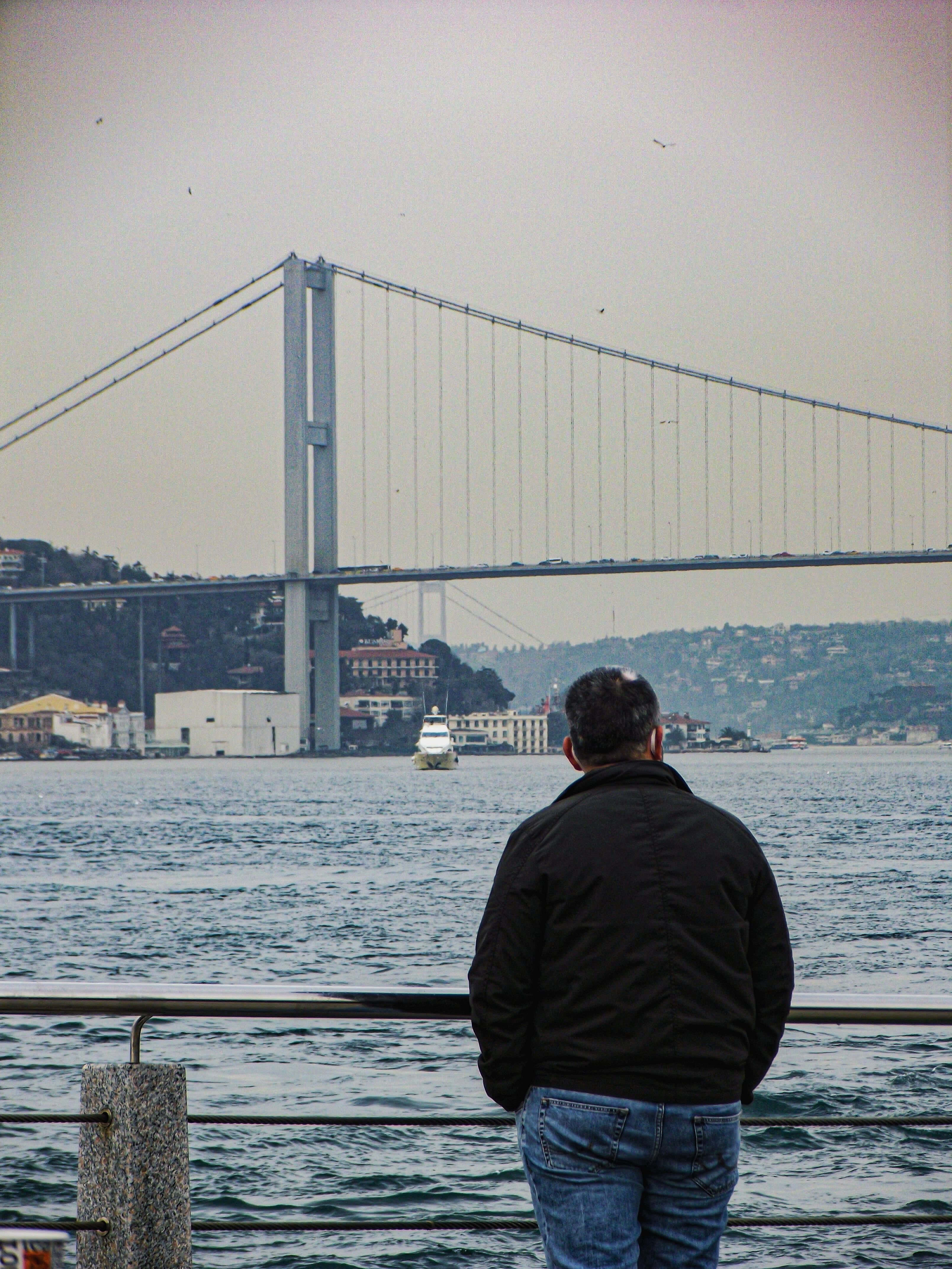 Man in Black Jacket Standing Near Body of Water · Free Stock Photo