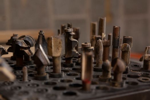 Set of weathered router bits placed in container with holes and storing in workshop of joiner