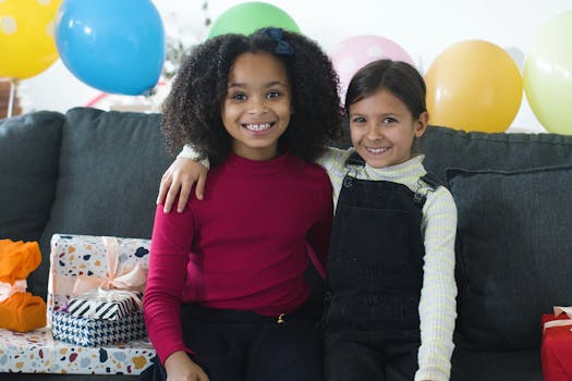 Two children enjoying a birthday celebration surrounded by colorful balloons and gifts indoors.