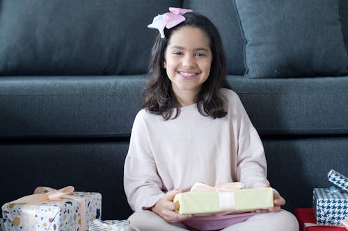 Girl with Pink Bow on Her Hand Holding a Gift Box and Smiling