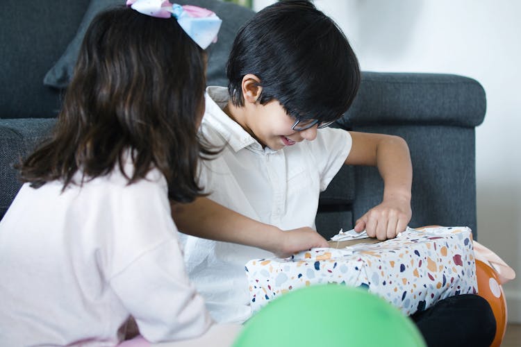 Boy In Glasses Unwrapping A Gift