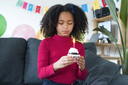 A Young Girl Holding a Cupcake with Lighted Candle