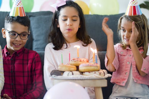 Free Kids Sitting on the Floor Near a Plate of Donuts with Candles Stock Photo