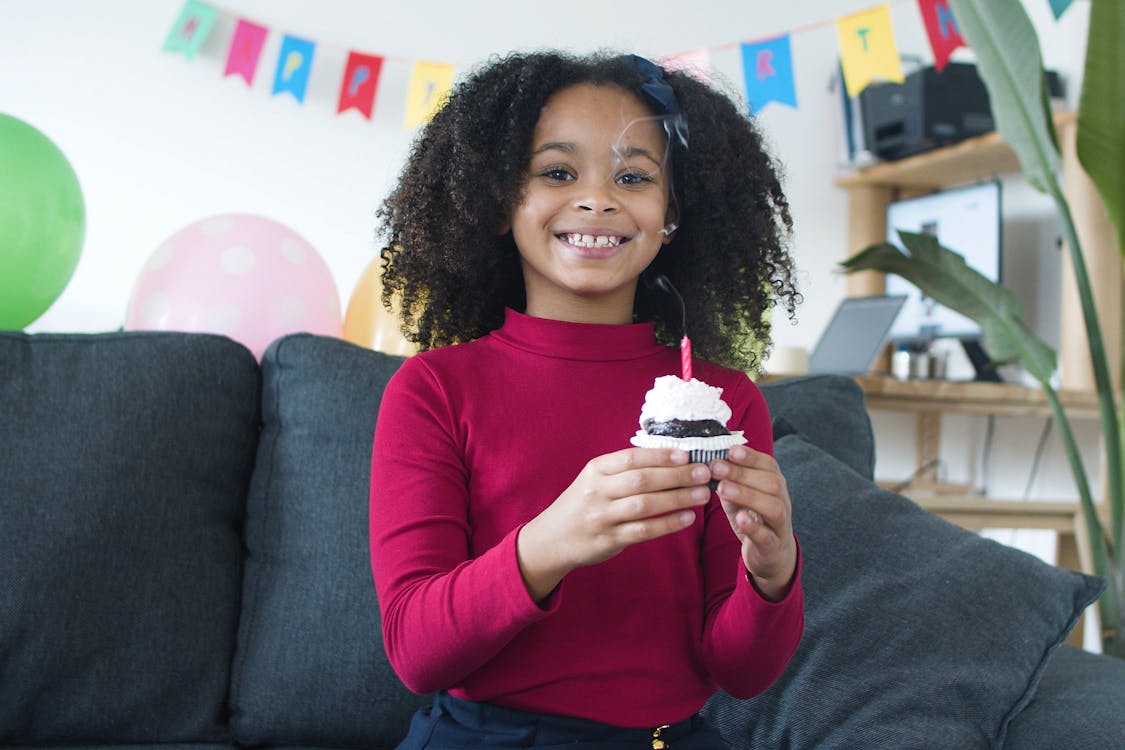 A Girl Holding a Cupcake with a Candle