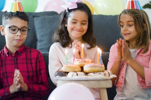 A joyful birthday celebration with children and sparkling candles on donuts.