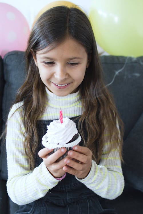 Girl in White Sweater Holding a Cupcake with a Candle