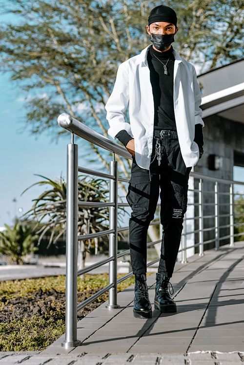 Free Man in contemporary street fashion with mask outdoors by railings. Stock Photo