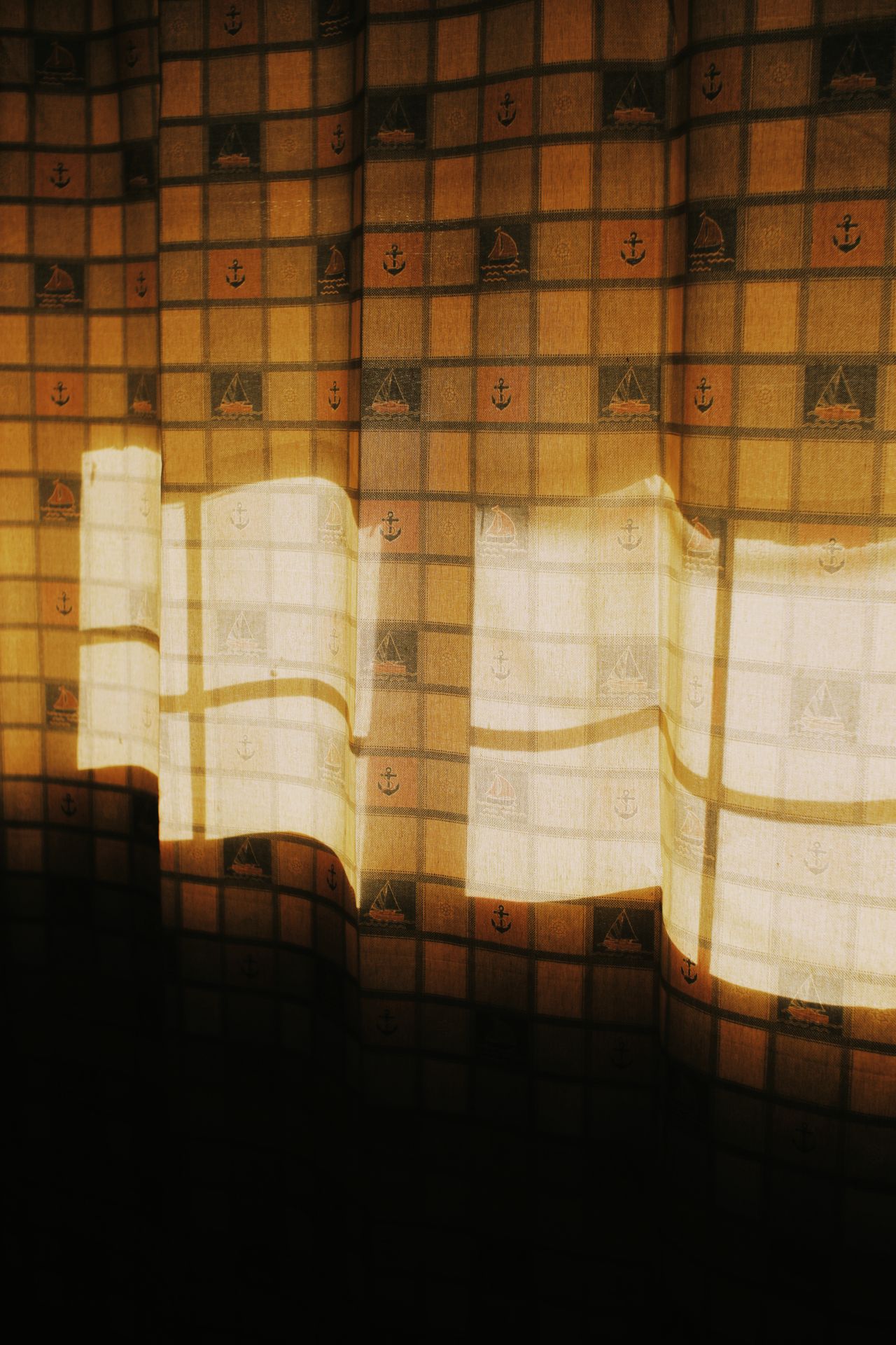 Patterned curtains with nautical motifs glowing in window light