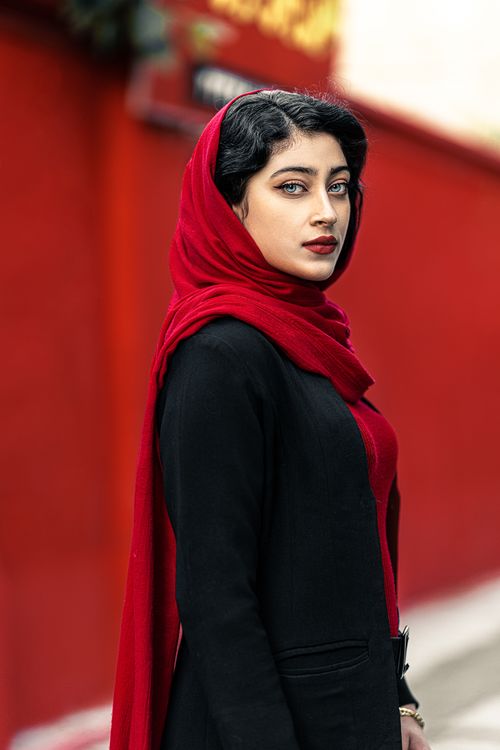 Free Striking portrait of a woman in a vibrant red headscarf against a red background, exuding elegance and style. Stock Photo
