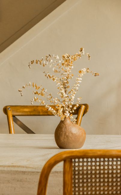 Stylish dried flower arrangement in a ceramic vase on a wooden table, perfect for adding warmth to home decor.