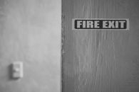 Black and white of wall with inscription Fire exit in room in daytime