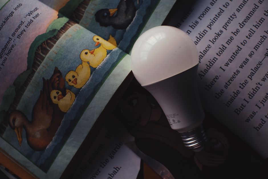From above of light bulb placed on opened books for children with illustrations