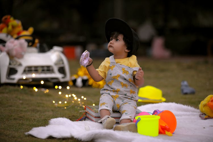 A Cute Baby Sitting On The Stack Of Books While Looking Up