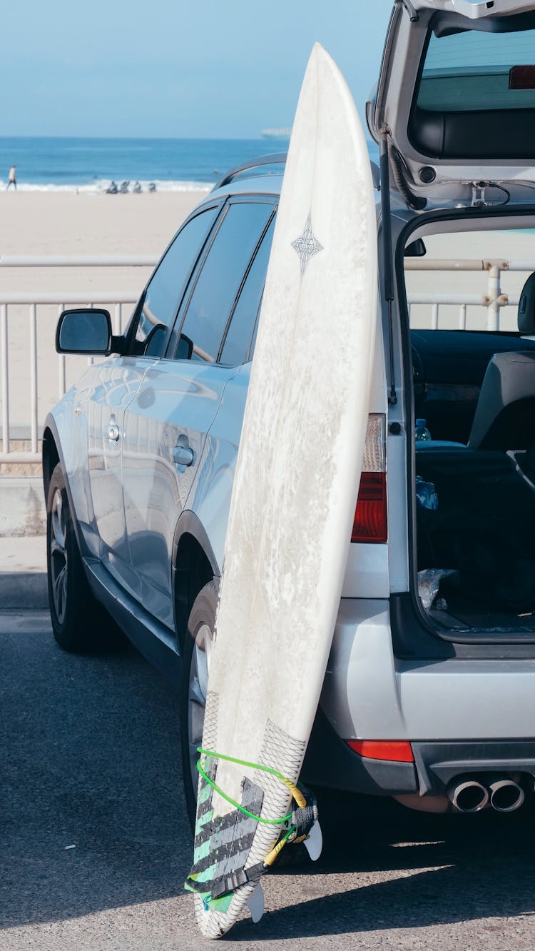 A Surfboard Leaning On The Parked Car