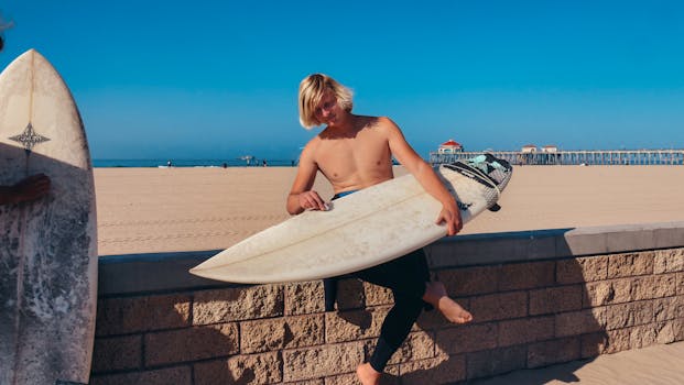 A young surfer sits on a wall with his surfboard at Huntington Beach, California.