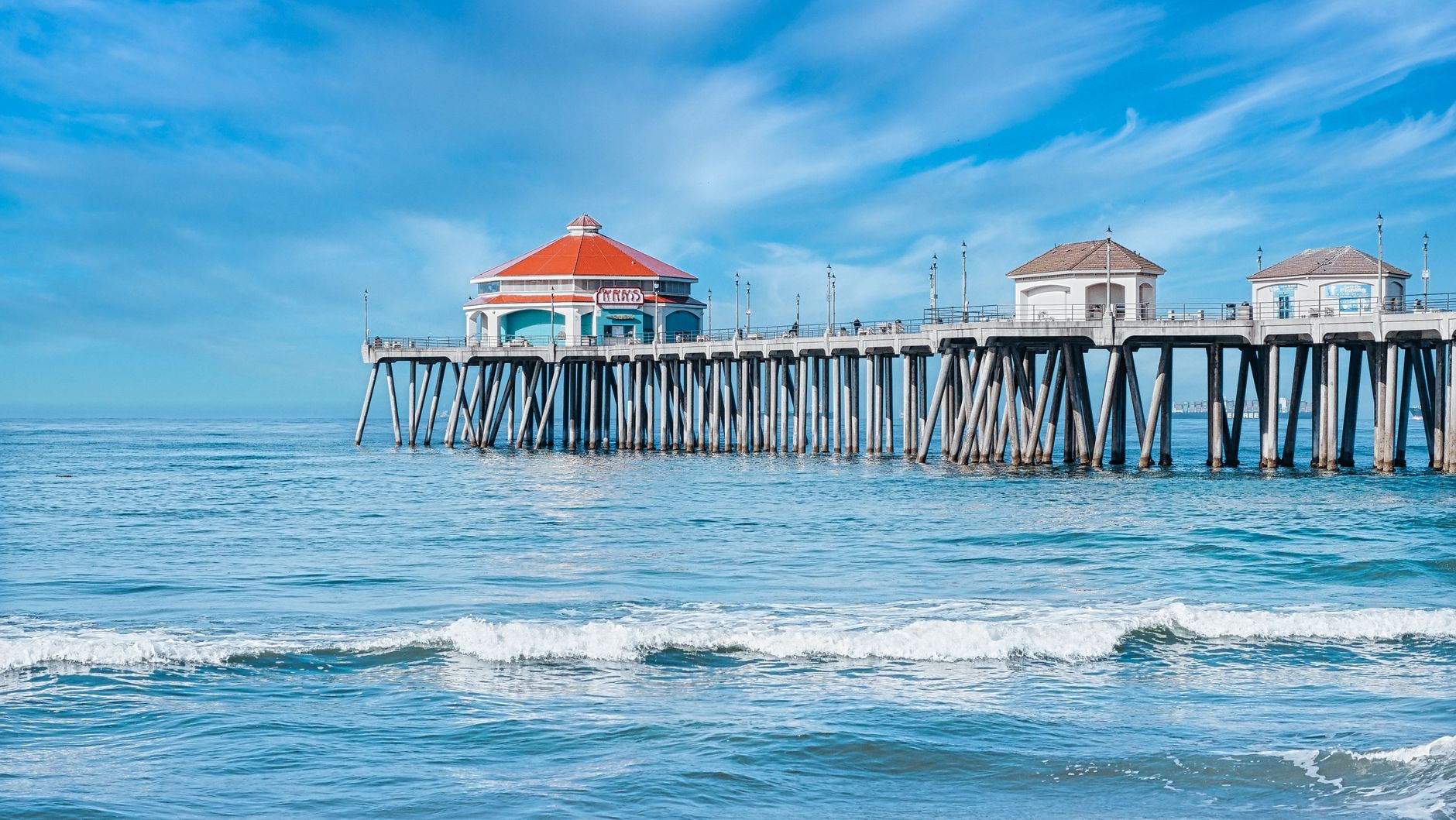 Scenic view of Huntington Beach Pier with waves and blue sky, perfect for a summer vacation vibe.